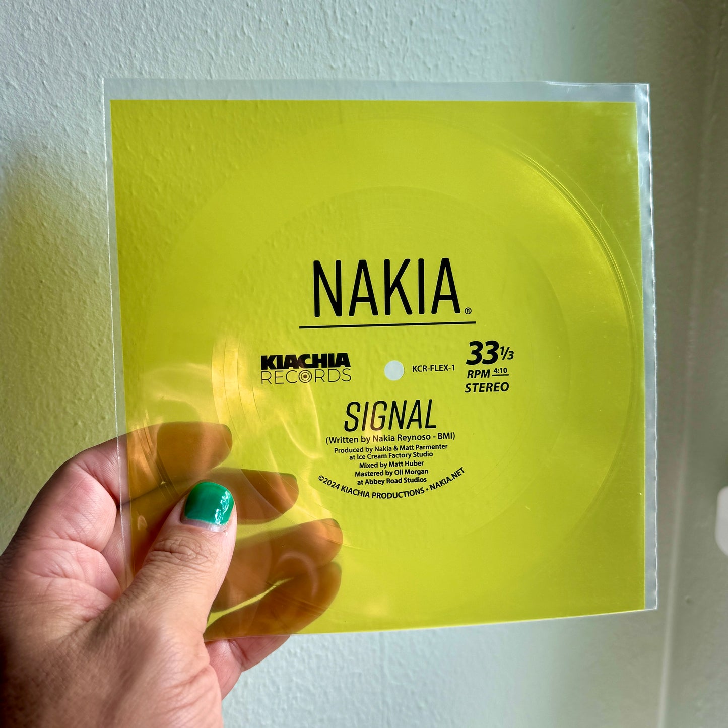 A hand holding a limited edition vinyl flexi-disc single of Nakia's song "Signal."