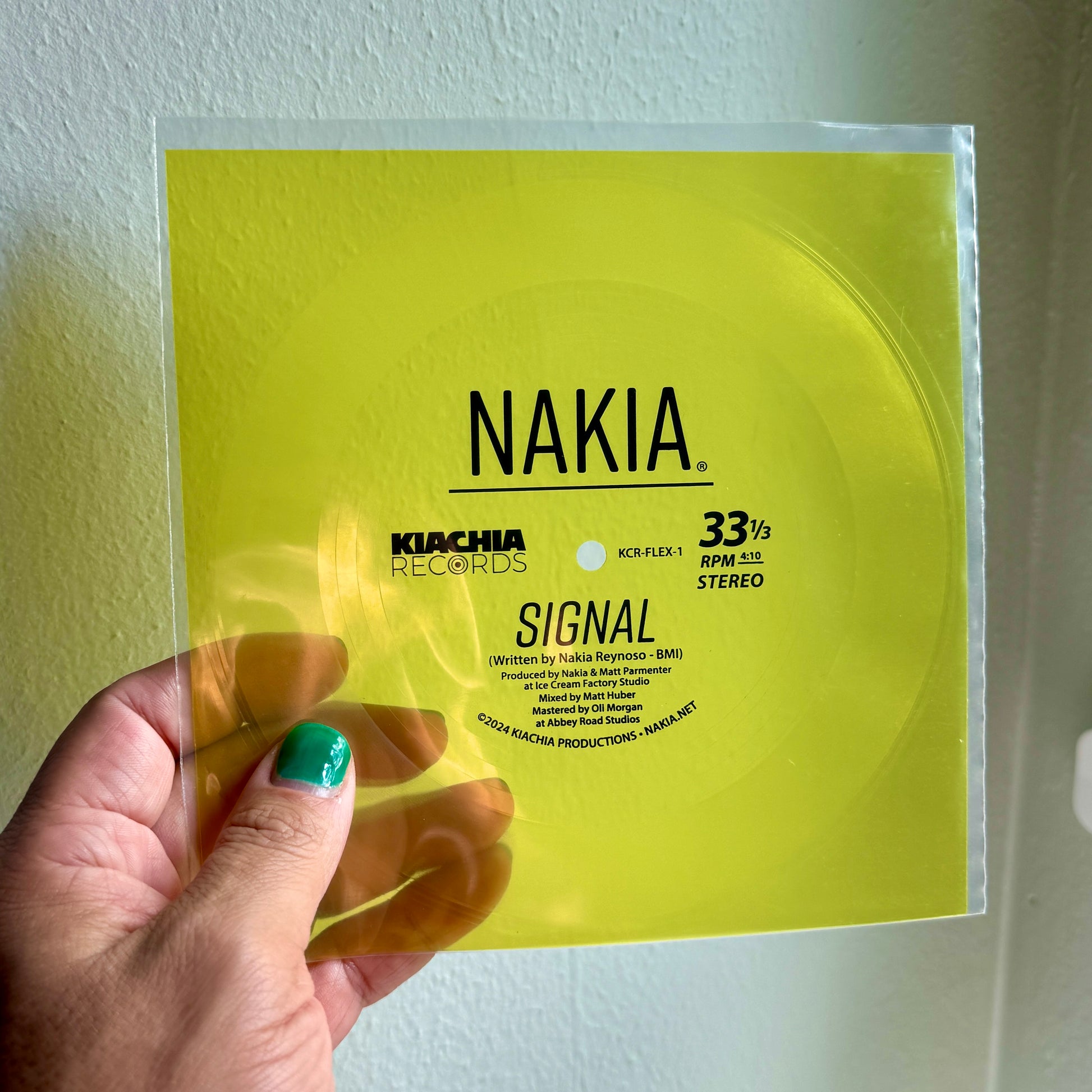 A hand holding a limited edition vinyl flexi-disc single of Nakia's song "Signal."